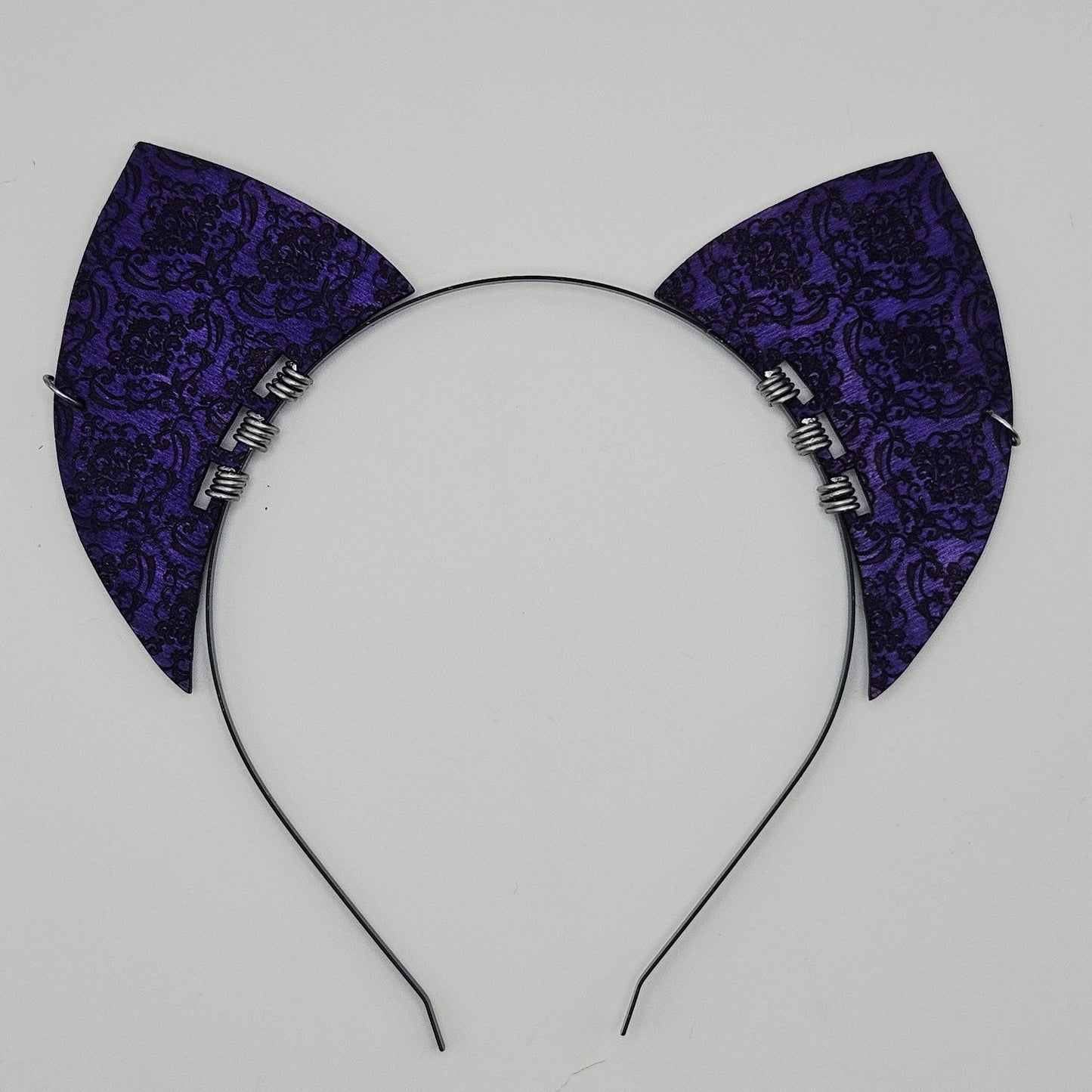 Purple brocade cat ear headband on a light gray background