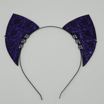 Purple brocade cat ear headband on a light gray background