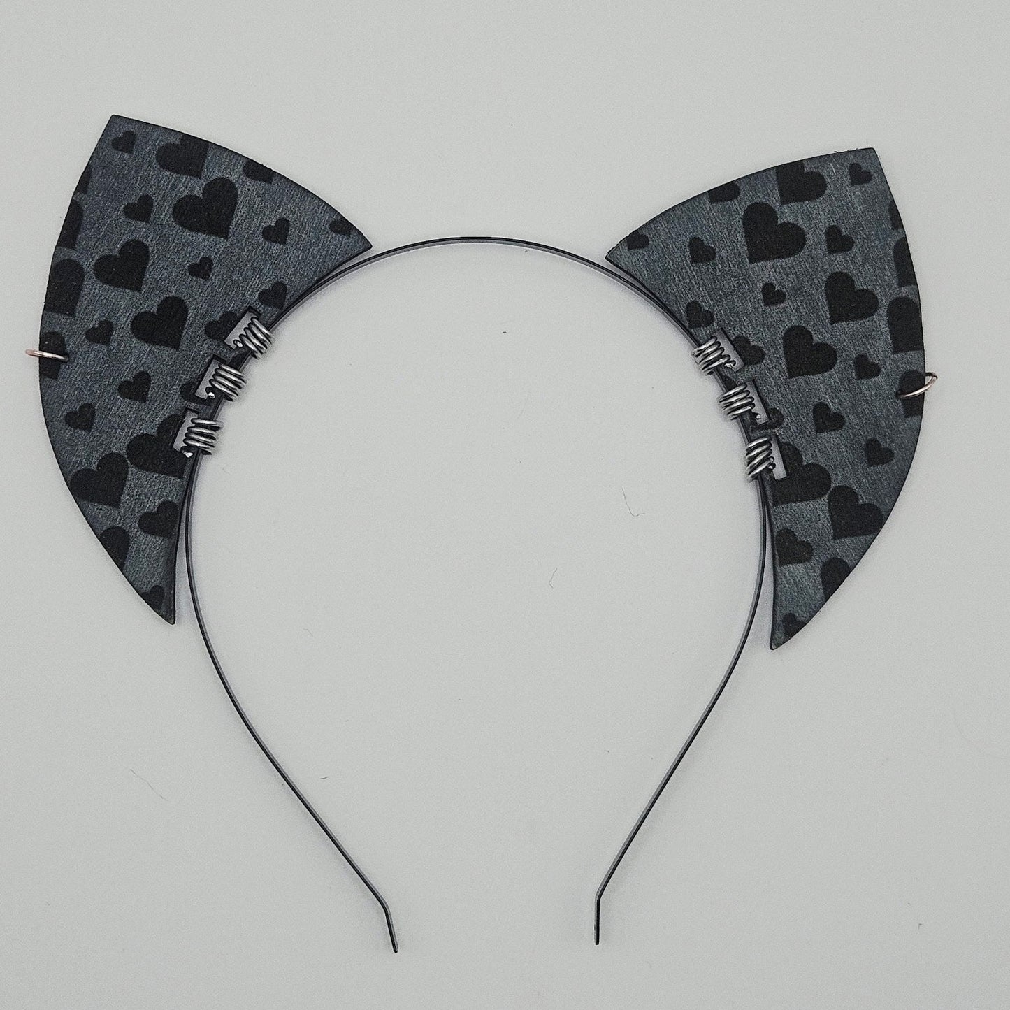 Cat ear headband with black heart pattern on a gray background