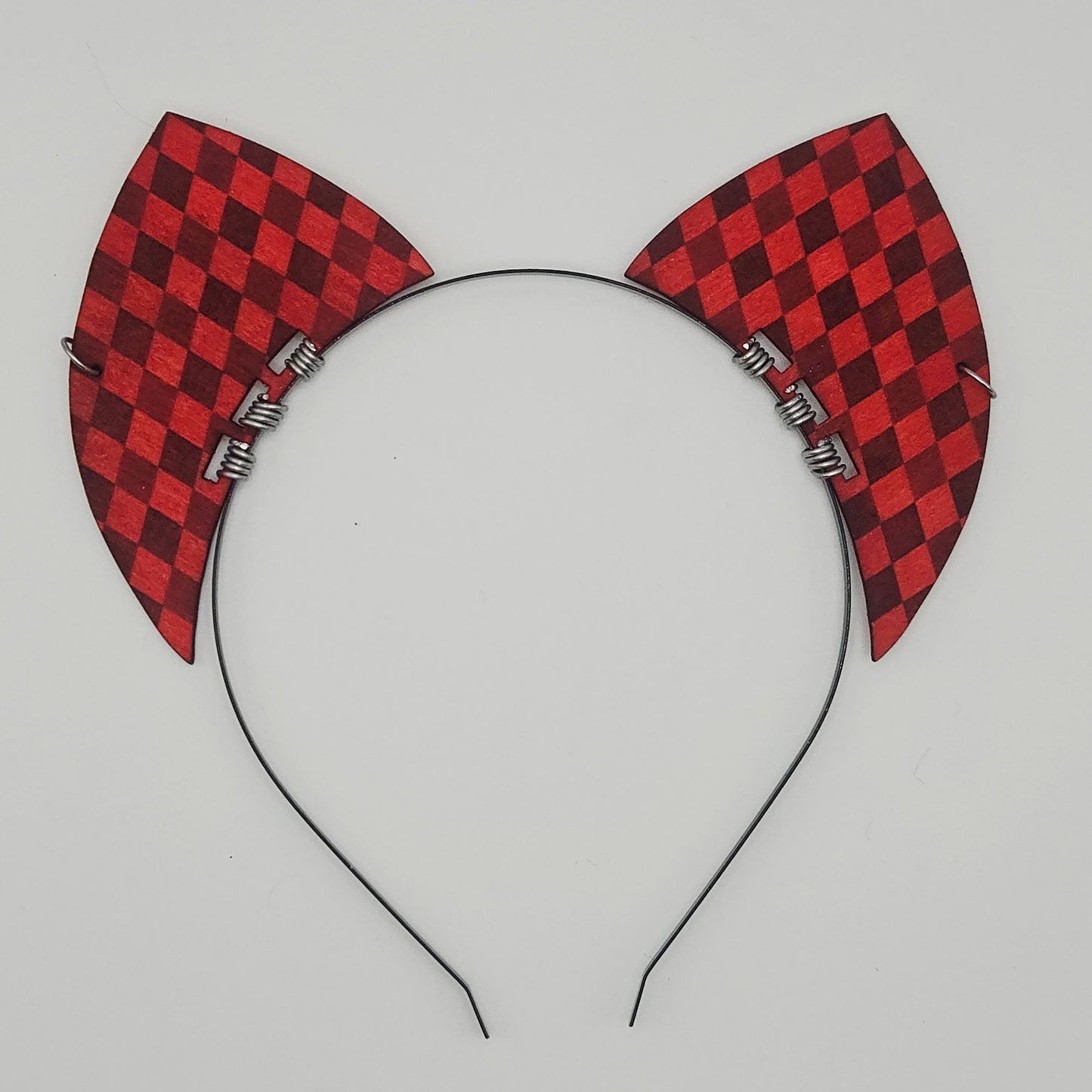 Red and black checkered cat ears on a headband against a light gray background